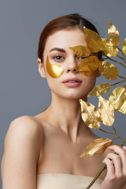 portrait woman golden leaves luxury skin care face patches bare shoulders isolated background - Photo, Image