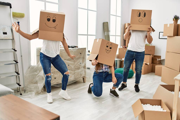 Mother and couple playing with funny cardboard box on head at home - Photo, Image