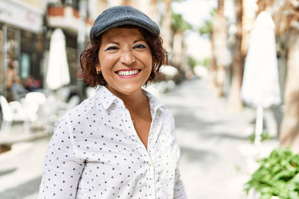 Orta yaşlı, gülümseyen Latin bir kadın şehirde mutlu bir şekilde duruyor.. - Fotoğraf, Görsel