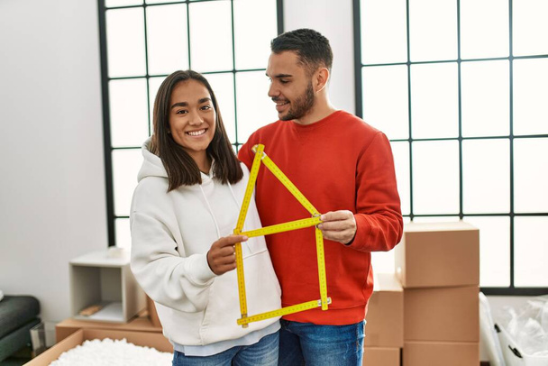 Jovem casal latino sorrindo feliz segurando projeto casa nova casa. - Foto, Imagem