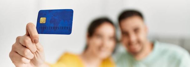 Jovem casal hispânico segurando cartão de crédito em casa. - Foto, Imagem