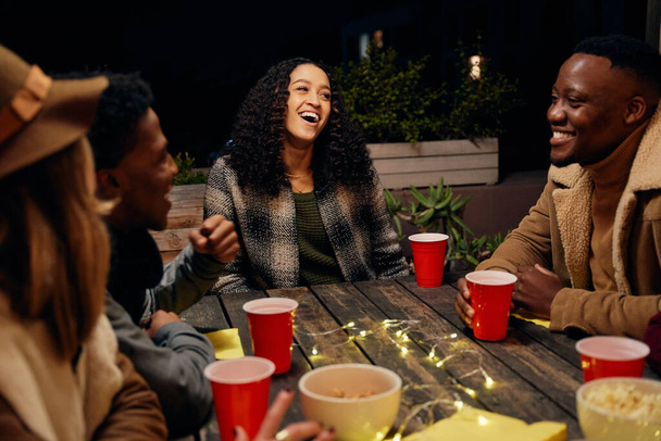 Biracial female smiling with group of diverse young adults sitting at boho themed rooftop party celebrating  - Zdjęcie, obraz