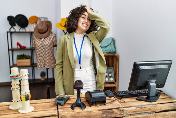 Young middle eastern woman working as manager at retail boutique surprised with hand on head for mistake, remember error. forgot, bad memory concept.  - Foto, Imagen