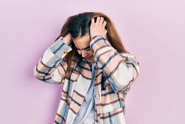 Junge kaukasische Mädchen in lässiger Kleidung leiden unter Kopfschmerzen verzweifelt und gestresst, weil Schmerzen und Migräne. Hände auf den Kopf.  - Foto, Bild