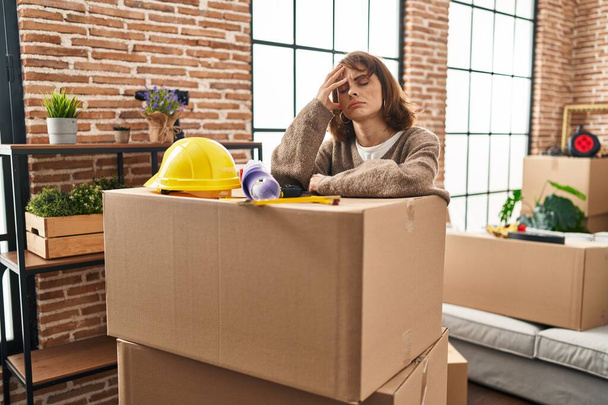 Young caucasian woman worried leaning on package at new home - Photo, Image