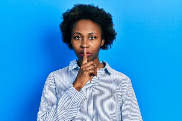 A fiatal afro-amerikai nő alkalmi ruhát visel, és azt kéri, hogy maradjon csendben, ujjal a száján. csend és titkos koncepció.  - Fotó, kép