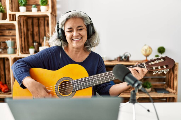 中世白髪の女性は、ラジオスタジオで働くギターを演奏. - 写真・画像