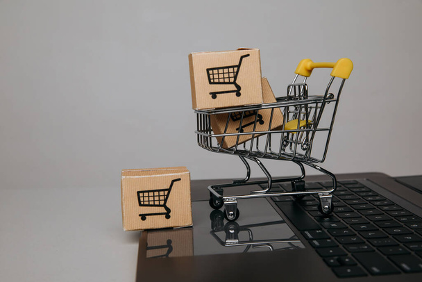 Online sales concept. Trolley with paper boxes on a keyboard - Fotó, kép