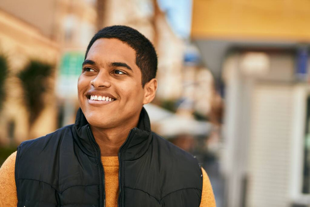 Молодий латинський чоловік усміхається щасливий стоячи в місті
 - Фото, зображення