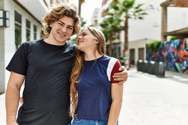 A fiatal fehér pár boldogan mosolyog és ölelkezik a városban.. - Fotó, kép
