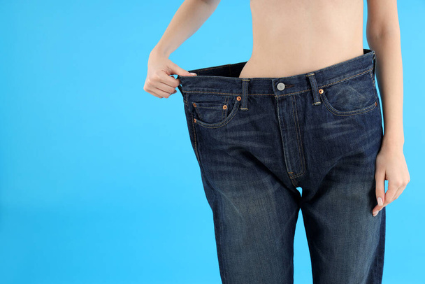 Έννοια της απώλειας βάρους με νεαρή λεπτή γυναίκα σε μπλε φόντο - Φωτογραφία, εικόνα