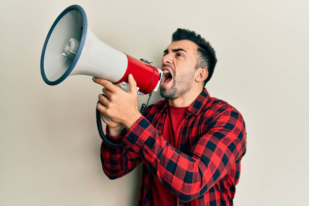 Hispanic man with beard screaming with megaphone - Фото, зображення