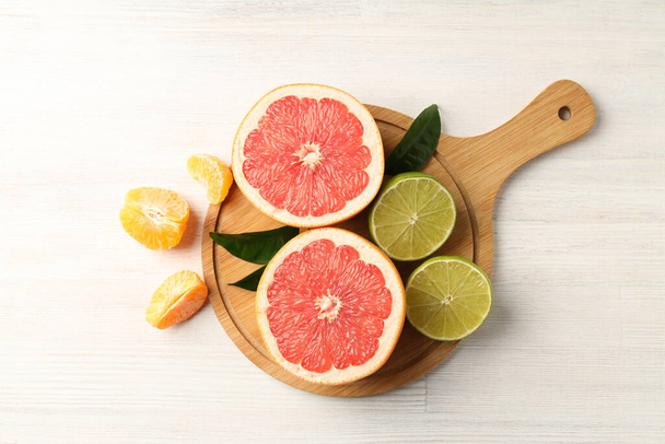 Board with citrus fruits on white wooden background - Photo, Image