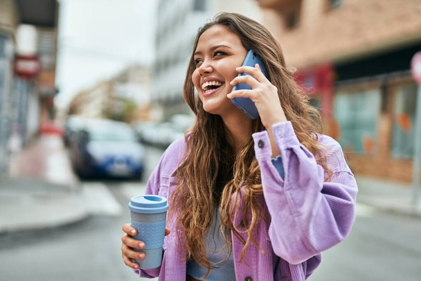 Fiatal spanyol nő beszél az okostelefonon kávézás a városban. - Fotó, kép