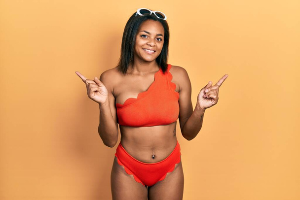 Young african american girl wearing bikini smiling confident pointing with fingers to different directions. copy space for advertisement  - Fotografie, Obrázek