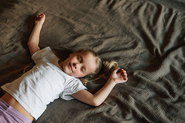 portrét usměvavého dítěte spícího doma na posteli rodičů. Kvalitní fotografie - Fotografie, Obrázek