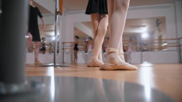 Entrenamiento de ballet - grupo de niñas entrenando ballet en el estudio del espejo - dos de ellas entrenando aparte de otras cerca del stand - Imágenes, Vídeo