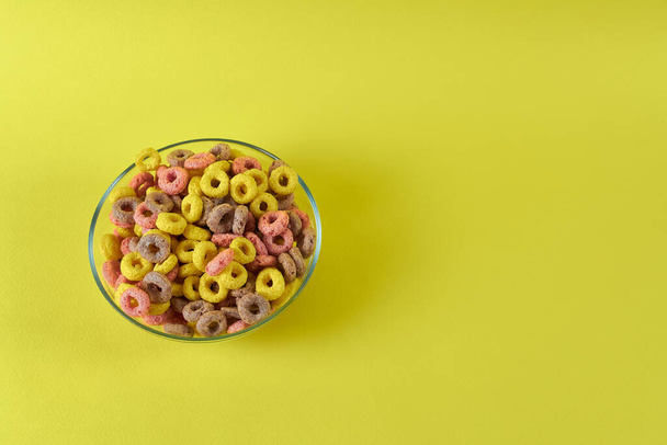 talíř s pestrobarevnými kruhy z obilovin na žlutém pozadí - Fotografie, Obrázek