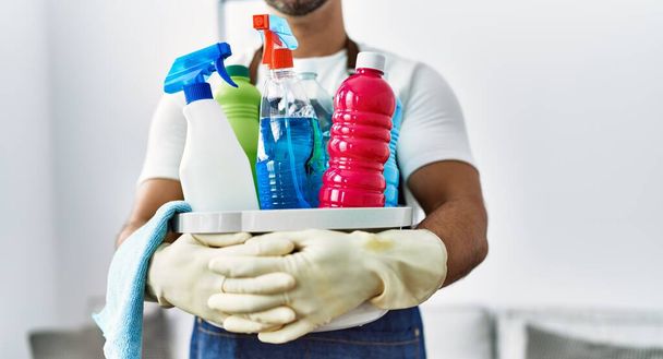 Jeune homme hispanique tenant des produits de nettoyage à la maison - Photo, image