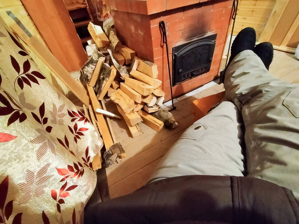 Mężczyzna odpoczywa przy kominku w chłodnym domu zimą. - Zdjęcie, obraz