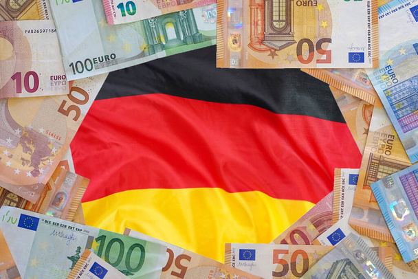 Макап банкнот евро на фоне флага Германии. Различные евробанкноты рамка. Бизнес, финансы, инвестиции, сбережения и коррупция концепции Европы - Фото, изображение