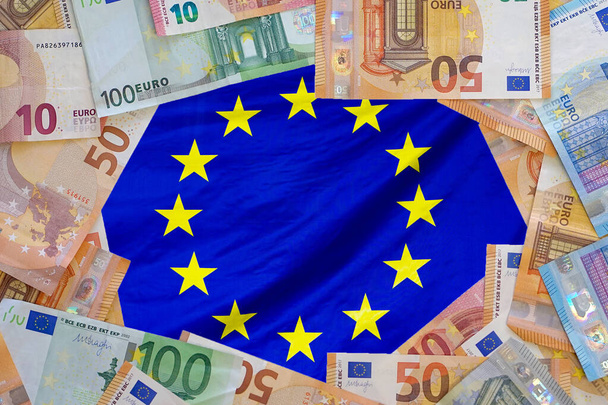 Avrupa Birliği bayraklarının arka planında Avro banknotlarından Macup. Farklı Euro banknotları çerçevesi. İş, finans, yatırım, tasarruf ve Avrupa yolsuzluk kavramı - Fotoğraf, Görsel