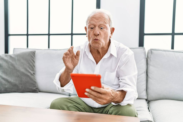 Senior homme souriant confiant ayant appel vidéo à la maison - Photo, image