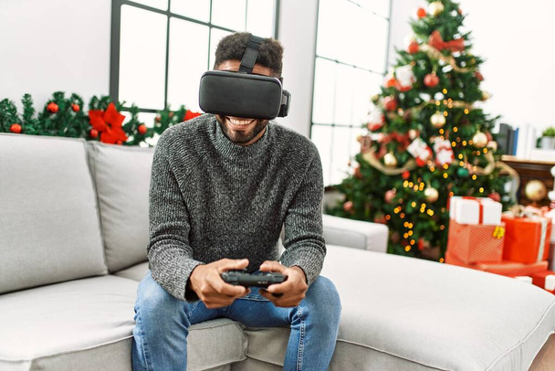 Νέοι Αφροαμερικανοί γιορτάζουν τα Χριστούγεννα παίζοντας βιντεοπαιχνίδι εικονικής πραγματικότητας στο σπίτι. - Φωτογραφία, εικόνα