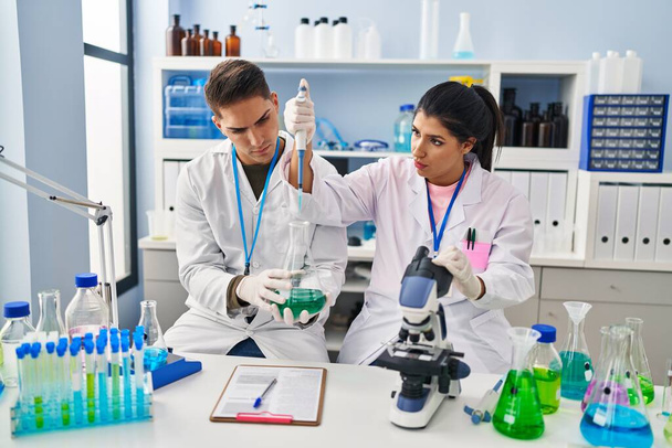 Homme et femme scientifiques partenaires utilisant la pipette au laboratoire - Photo, image