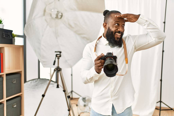 Африканский американский фотограф, работающий в фотостудии, очень счастлив и улыбается, глядя вдаль с поднятой головой. поиск концепция.  - Фото, изображение