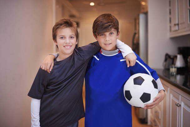 Jungen werden Jungen sein. Porträt zweier kleiner Jungen in Sportkleidung, die drinnen mit einem Fußballball stehen. - Foto, Bild