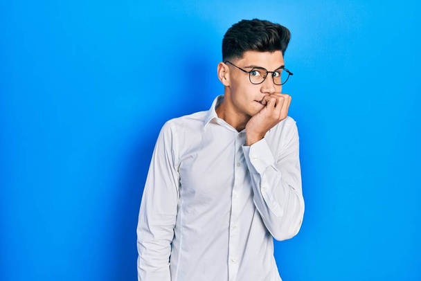 Young hispanic man wearing casual clothes and glasses looking stressed and nervous with hands on mouth biting nails. anxiety problem.  - Photo, Image