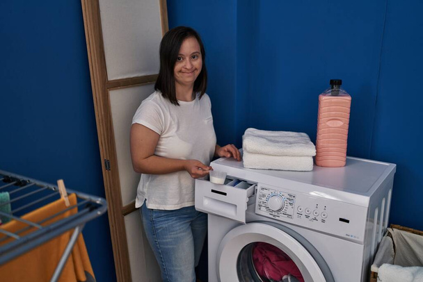 Down syndrome woman smiling confident pouring detergent on washing machine at laundry room - Valokuva, kuva