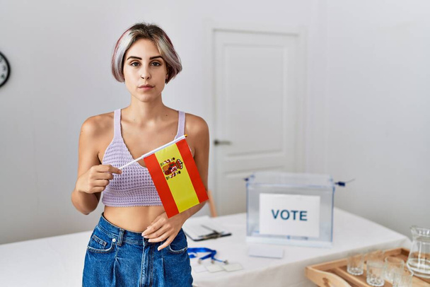 政治運動の選挙でスペインの旗を保持する若い美しい女性思考態度と自信を持っている自分自身を見て冷静に表現  - 写真・画像