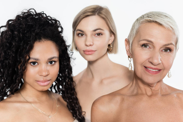 Interracial women with naked shoulders looking at camera near blurred friend isolated on grey  - Fotografie, Obrázek