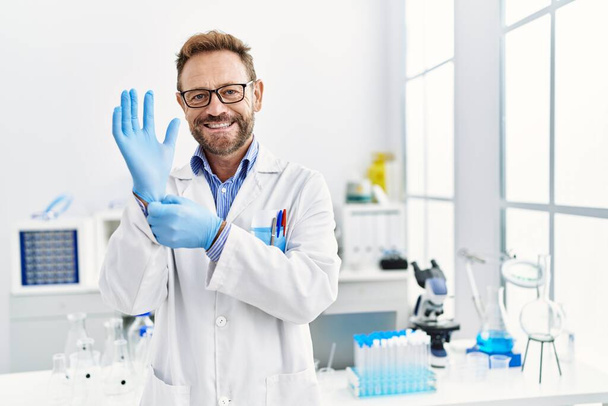 Hombre de mediana edad que trabaja en el laboratorio científico sonriendo con una sonrisa feliz y fresca en la cara. mostrando dientes.  - Foto, Imagen