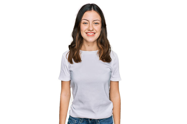 Jeune belle femme portant un t-shirt blanc décontracté avec un sourire heureux et cool sur le visage. chanceux.  - Photo, image