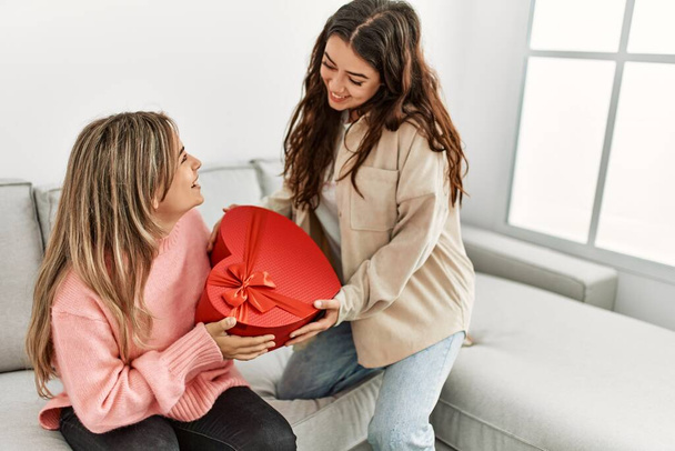 Young woman surprising her girlfriend with valentine gift at home. - Valokuva, kuva