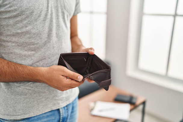 Jeune homme hispanique montrant portefeuille vide debout à la maison - Photo, image