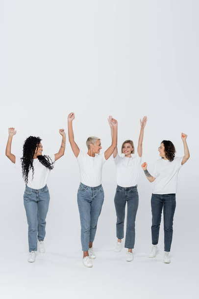Femmes multiethniques positives levant la main sur fond gris, concept de féminisme - Photo, image