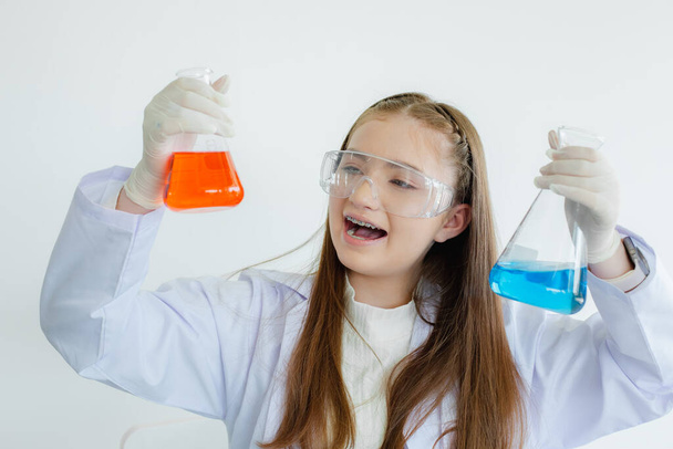 dziecko dziewczyna nauka studenci badania płynnych eksperymentów chemicznych w białym pokoju laboratoryjnym. Uczennica trzymająca probówkę z nauką biotechnologii. koncepcja edukacji naukowej. - Zdjęcie, obraz