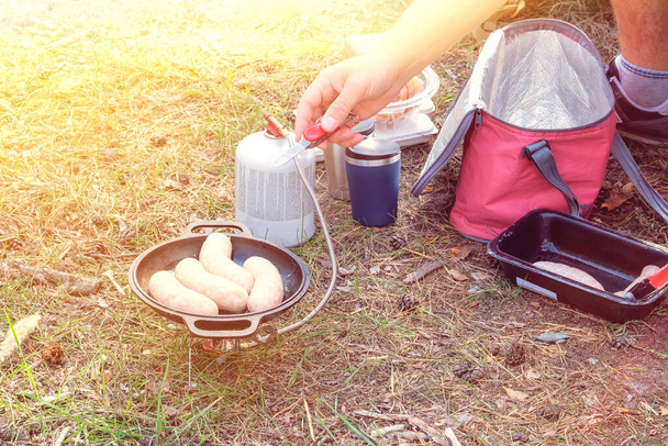 Żywność dla podróżujących na świeżym powietrzu. Kemping jedzenie podejmowania w podróży. Kiełbaski w garnku w lesie w słoneczny dzień.  - Zdjęcie, obraz