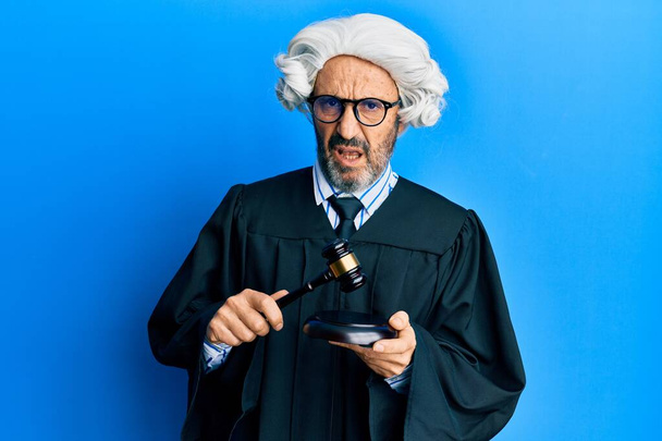 Middle age hispanic man using gavel clueless and confused expression. doubt concept.  - Photo, Image
