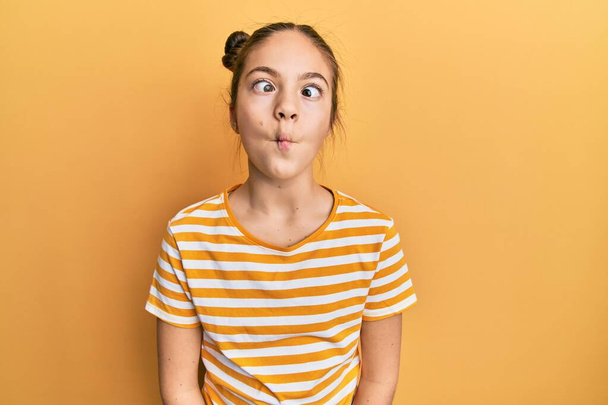 Όμορφη μελαχρινή κοριτσάκι φορώντας casual ριγέ t πουκάμισο κάνοντας ψαρομούρη με χείλη, τρελή και κωμική χειρονομία. αστεία έκφραση.  - Φωτογραφία, εικόνα