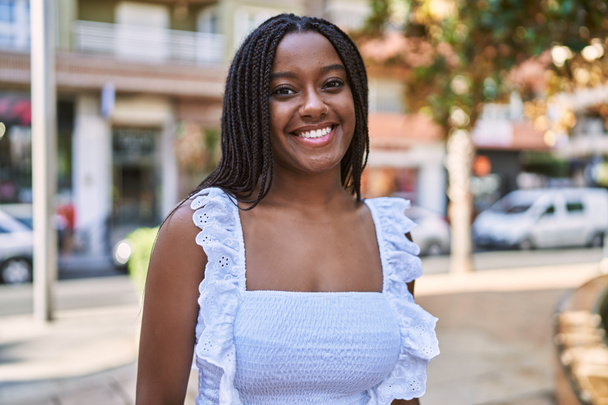 Jovem menina afro-americana sorrindo feliz de pé na cidade. - Foto, Imagem