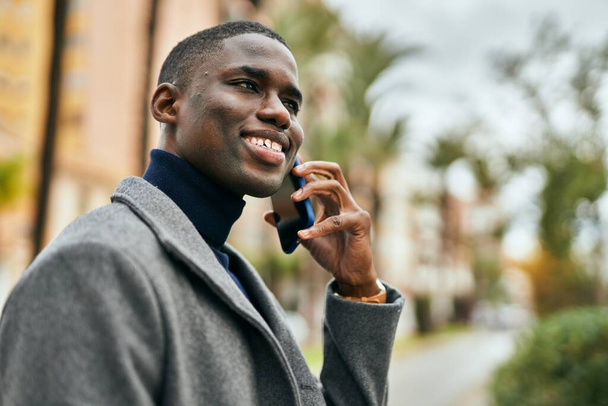 Nuori afrikkalainen amerikkalainen mies hymyilee onnellinen puhuu älypuhelimella kaupungin - Valokuva, kuva