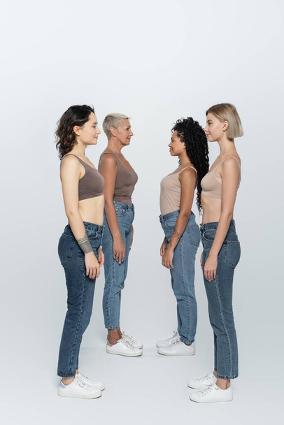 Side view of interracial women looking at each other on grey background  - Photo, image