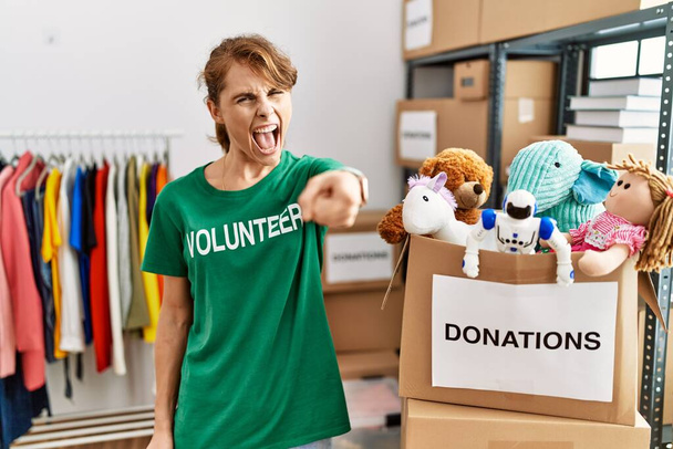 Schöne kaukasische Frau im freiwilligen T-Shirt am Spendenstand zeigt unzufrieden und frustriert in die Kamera, wütend und wütend auf dich  - Foto, Bild