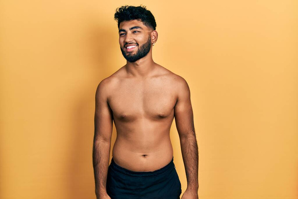 Arab man with beard wearing swimwear shirtless looking away to side with smile on face, natural expression. laughing confident.  - Photo, Image
