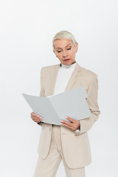 Femme d'affaires âgée en costume tenant dossier papier isolé sur gris  - Photo, image
